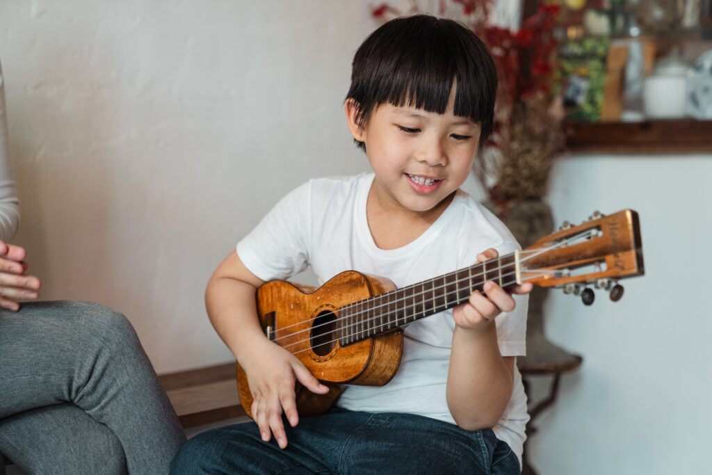 Small asian boy learning with wooden guitar