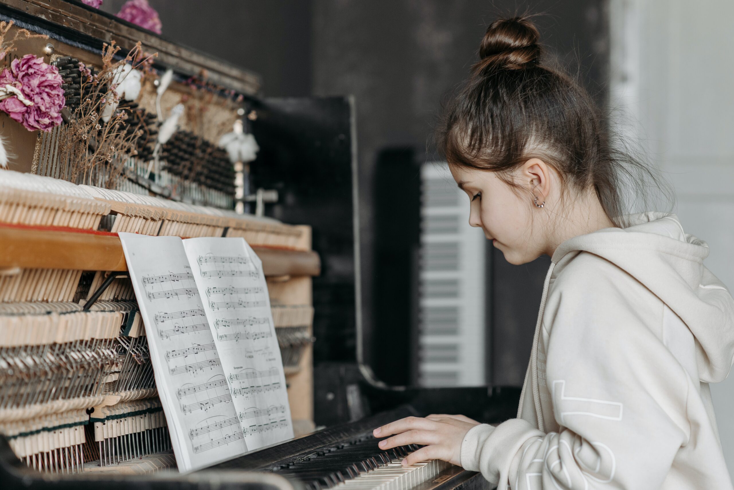 Little girl using music sheets to play the piano