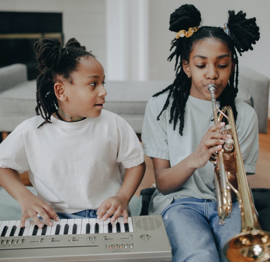Two African American girls playing the organ and trumpet
